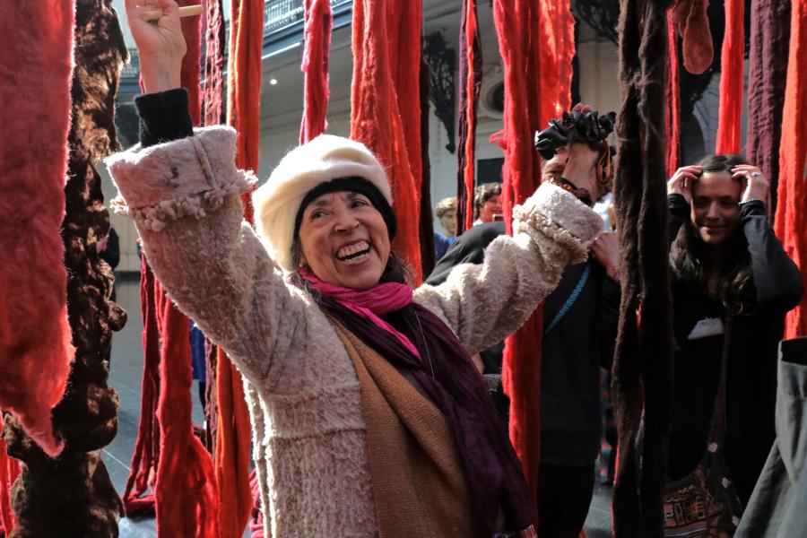 Mujer mayor riendo alrededor de telas de color rojo y naranja