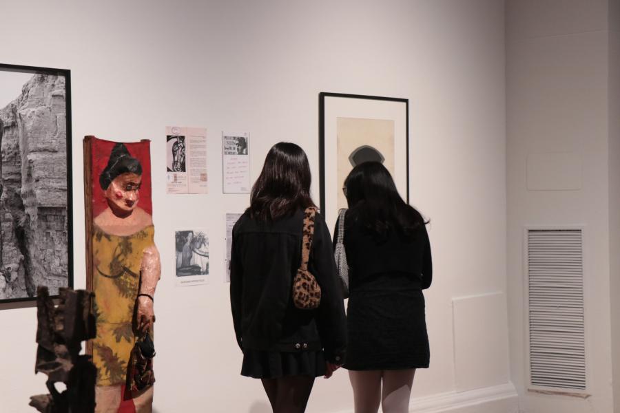 Dos personas observando las ilustraciones y textos de la muestra