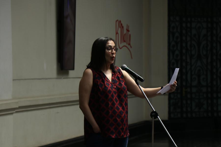 Mujer con cabello negro y lentes dando un discurso