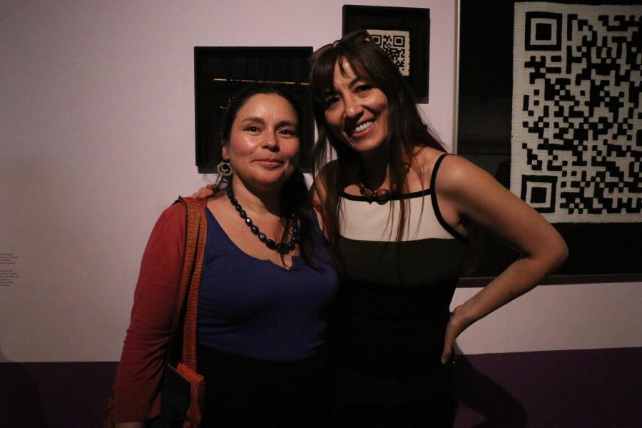 Dos mujeres en la sala de la muestra detrás de ellas hay un código qr pequeño y otro grande