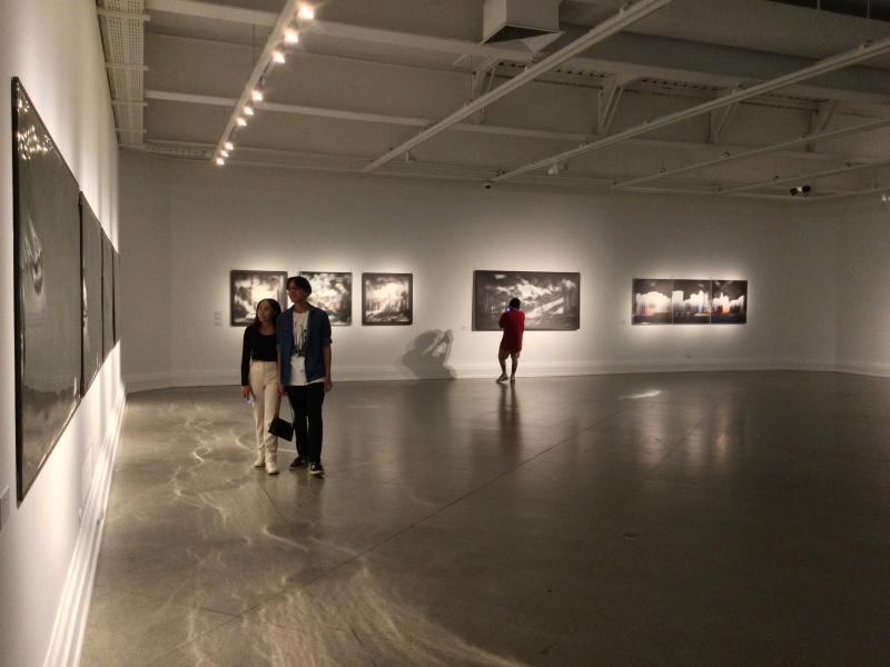 Una pareja observando los cuadros y un poco mas atras un hombre observando otro cuadro
