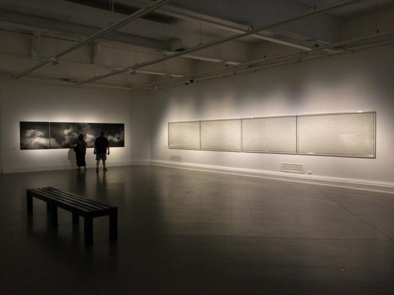 Dos personas observando los cuadros en la sala