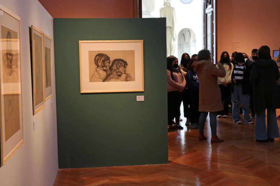 Se puede ver un cuadro con una ilustración en una pared verde y al lado de este hay personas