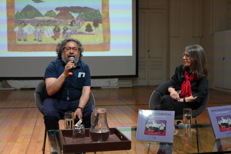 Un hombre presentando junto a una mujer sentados en un sillón